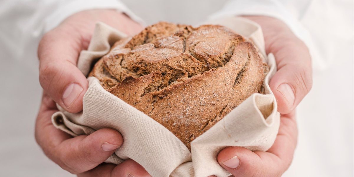 pezzo di pane senza glutine in mezzo a due mani avvolto da un tovagliolo