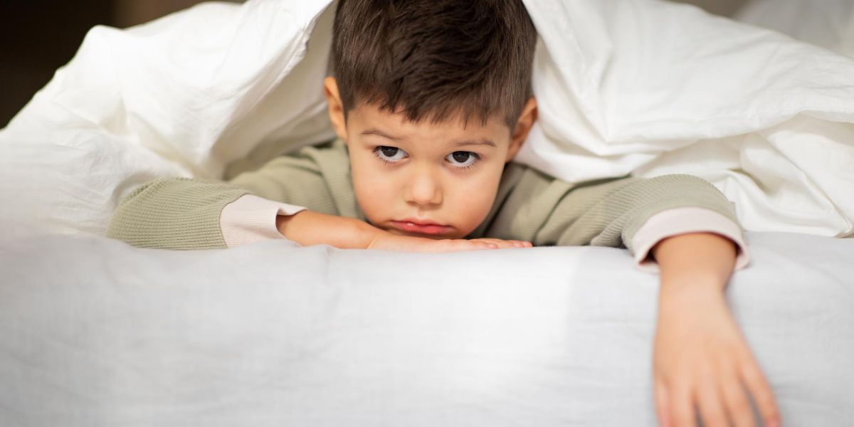 bambino sul letto a pancia sotto che non riesce a dormire e guarda il vuoto