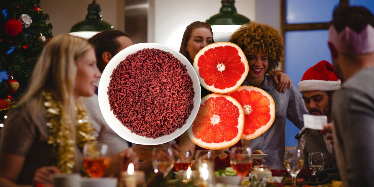 ciotola di lievito di riso rosso con delle fette di arancio amaro su sfondo di una famiglia che festeggia durante la cena di Natale