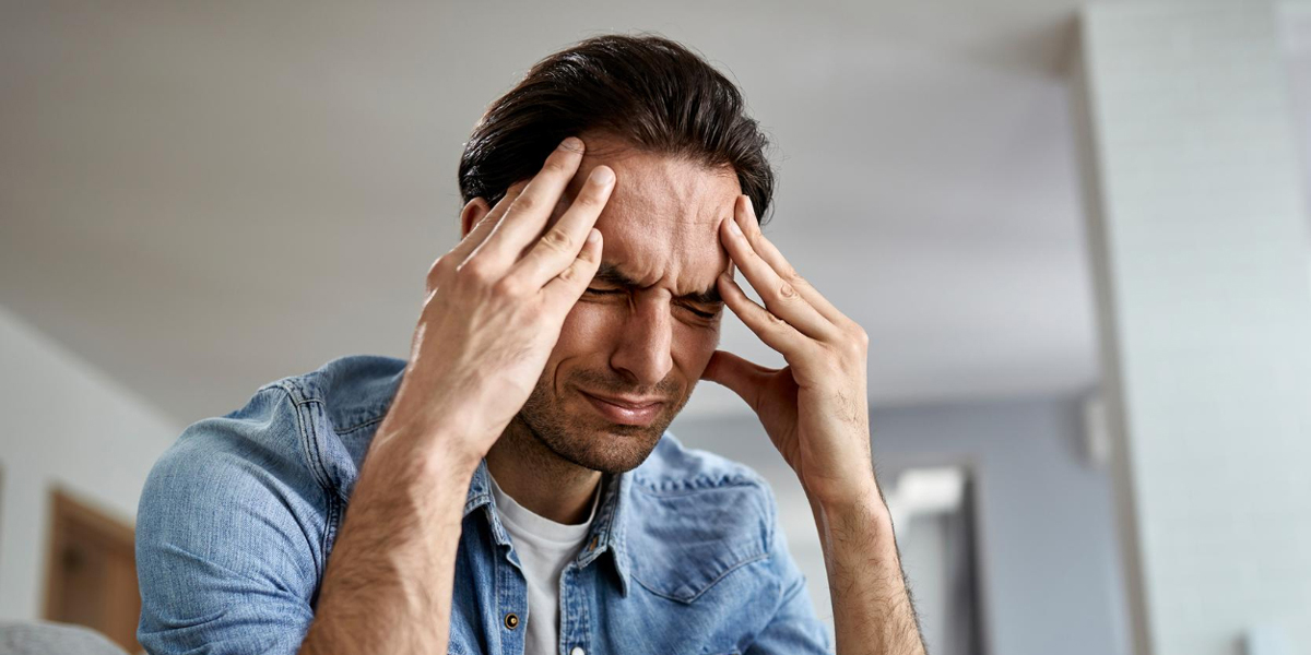 persona stressata piena di cortisolo che si mantiene la testa appoggiando le dita sulle sue tempie